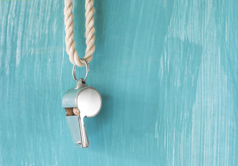 iStock-1440253188-whistle-blue_WEB silver whistle hanging from a rope on blue painted background